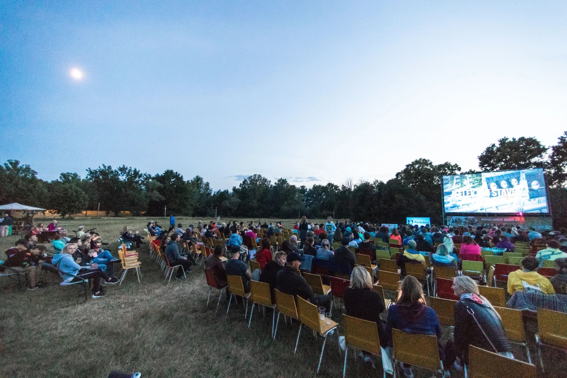 Projection sur écran géant en plein air devant un public au crépuscule