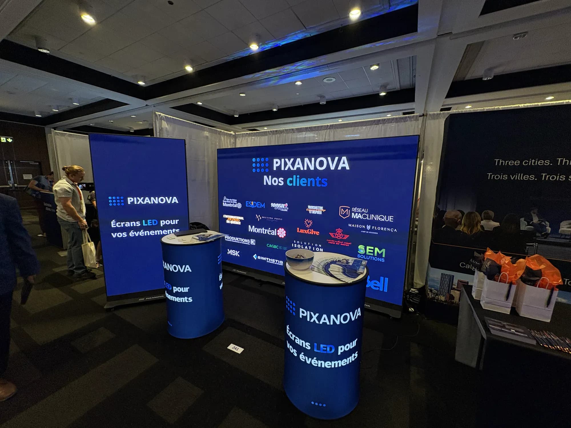 Kiosque Pixanova au Salon Momentum : mur de logos clients et écrans LED totem